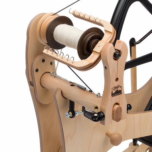 Wooden spinning wheel with a spool of yarn on a white background