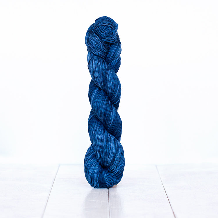 1216, a dark denim blue pink skein of Urth Yarn's hand-dyed Monokrom Cotton DK weight yarn.