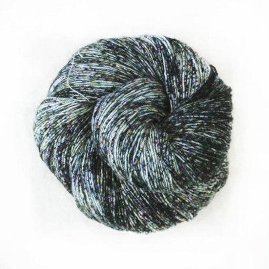 Malabrigo Mechita Monte Yarn - a white yarn speckled with green and dark grey