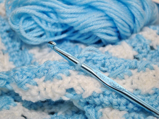crochet blanket project with a metal hook and the best yarn for blankets