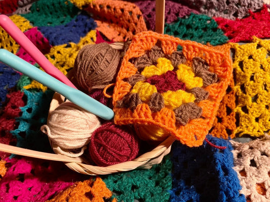 granny squares with yarn and hooks to show how much yarn to crochet a blanket