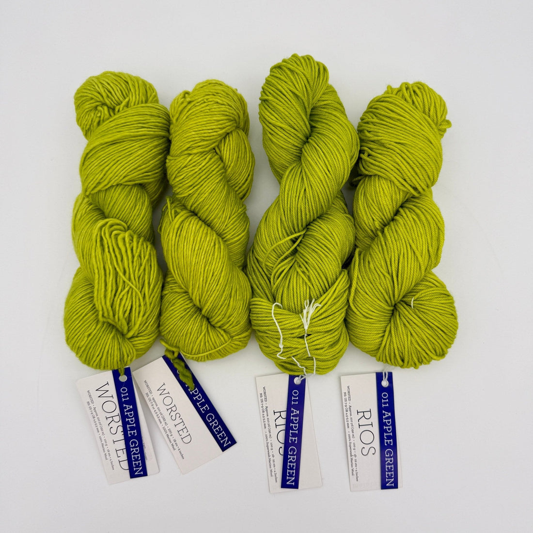 Two hanks of Malabrigo Worsted, a non-superwash merino, beside two hanks of Malabrigo Rios, a superwash merino, all in 011 Apple Green