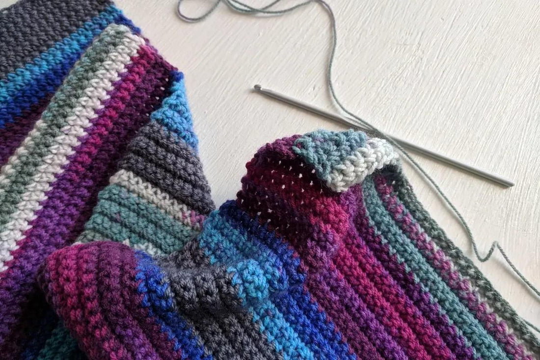 multicolored crocheted blanket fabric with a crochet hook