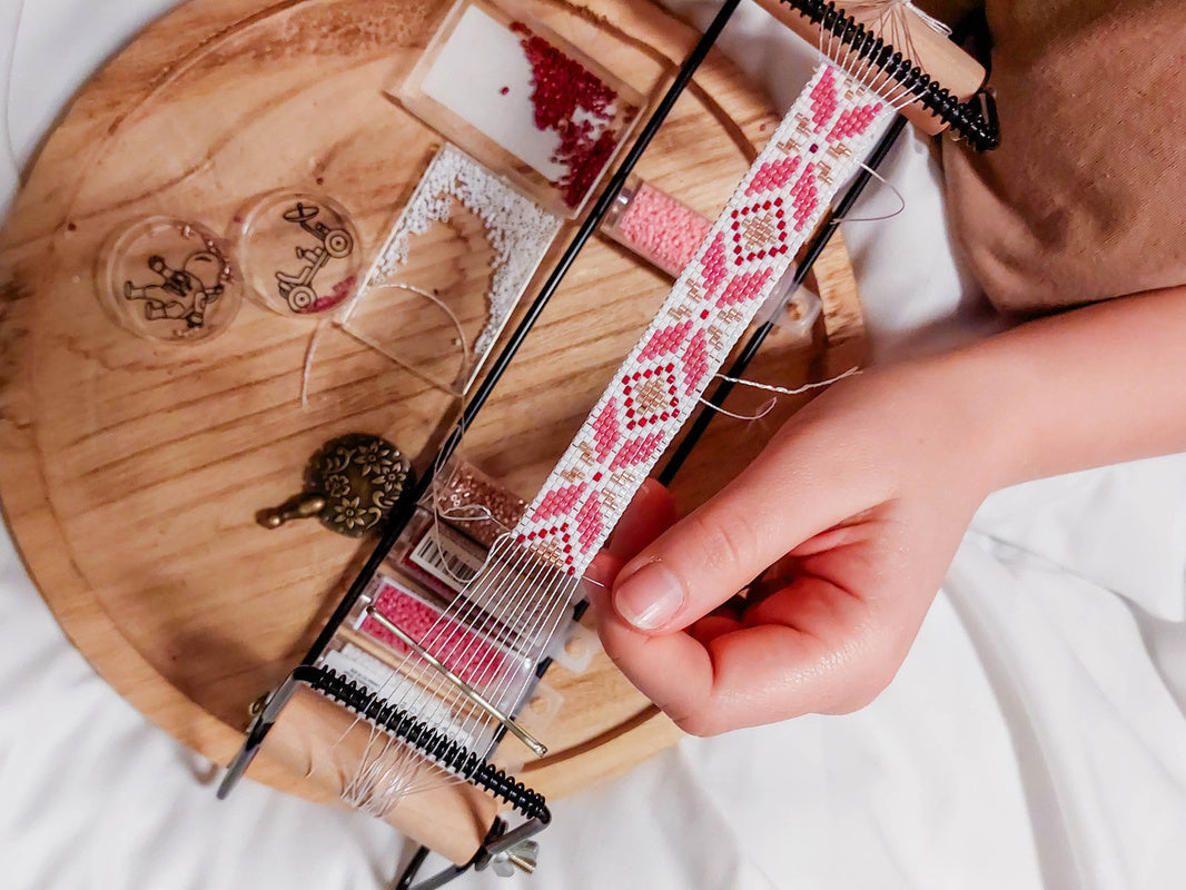person using a small at-home weaving setup to show what is a loom