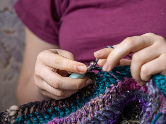 woman crocheting using the best yarn for a baby blanket