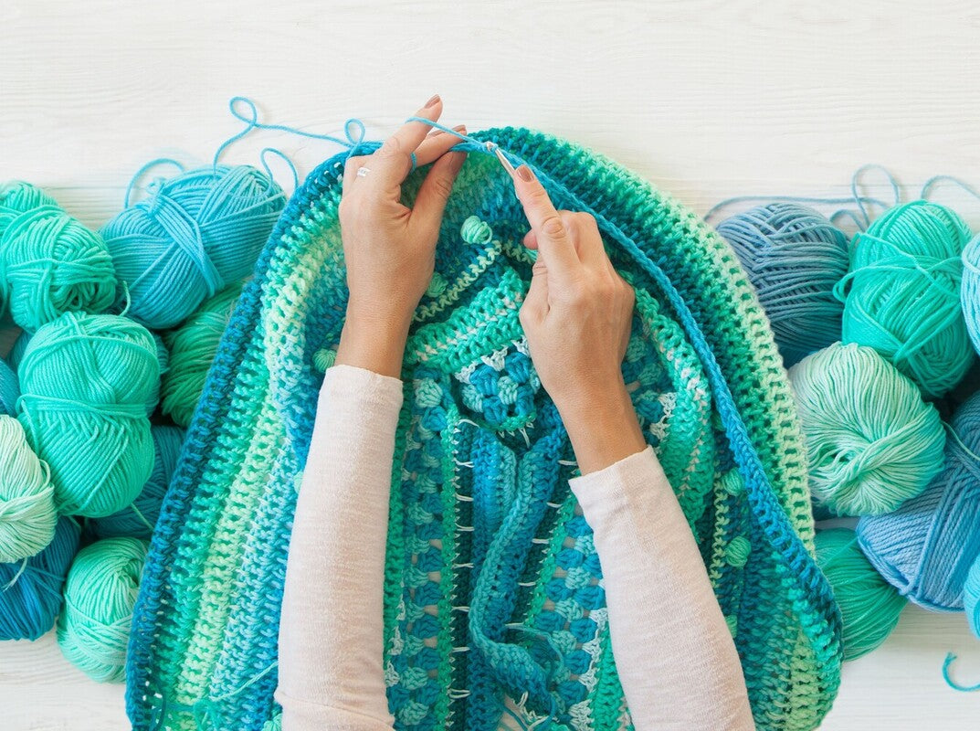 woman showing how to change yarn in crochet by using lots of different blue yarns
