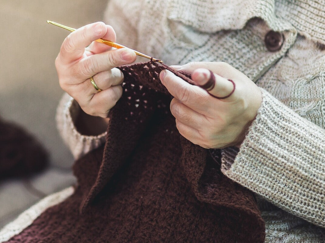 woman using the best yarn for scarf crochet to crochet a brown scarf