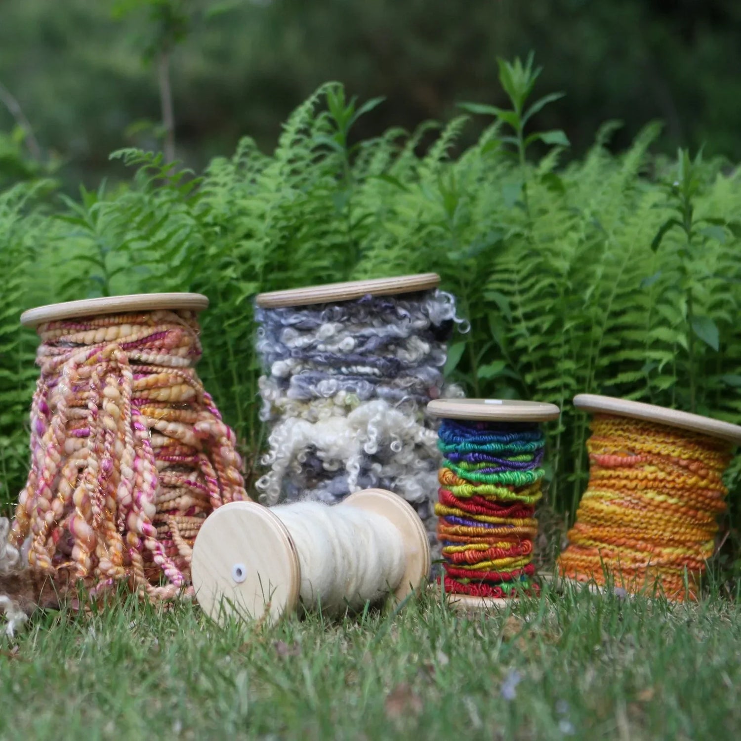 SpinOlution bobbins wound with yarn, displayed on grass