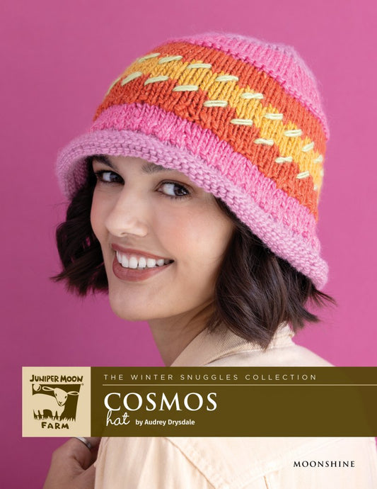 Woman smiling, wearing a pink, orange, and yellow knit hat.