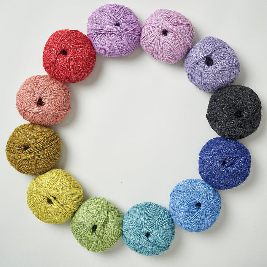 Balls of Rowan Felted tweed arranged in a circle in rainbow color order going counter clockwise. 
