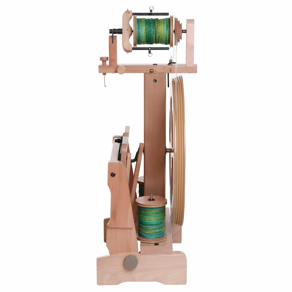 Wooden spinning wheel with spools of yarn on a white background