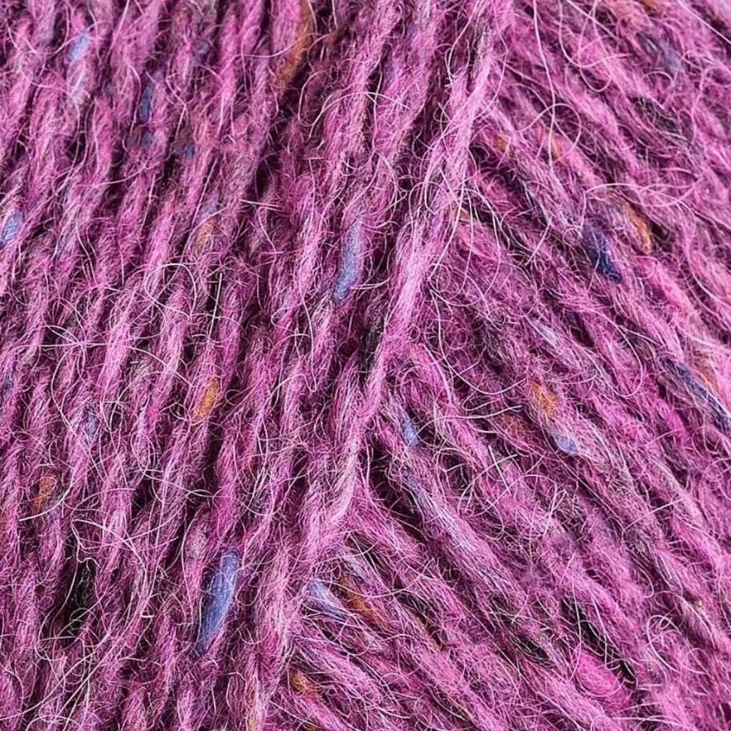 Peony 183: A heathered tweed yarn in a medium dusty fuschia color with flecks of orange and blue.