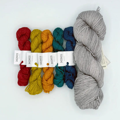 Set of colorful yarn mini skeins and a larger gray skein on a white background