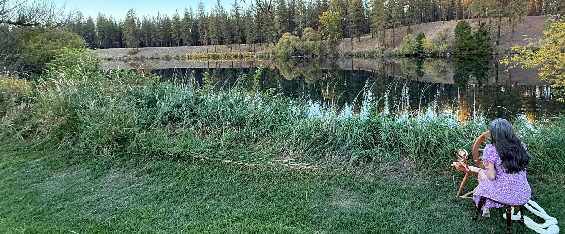 Sara sitting by the Spokane River surrounded by trees and grass and serene awesomeness