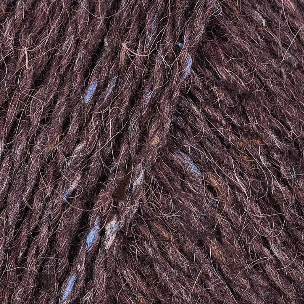 Treacle 145: A heathered tweed yarn in a deep chestnut brown color with flecks of orange and blue.