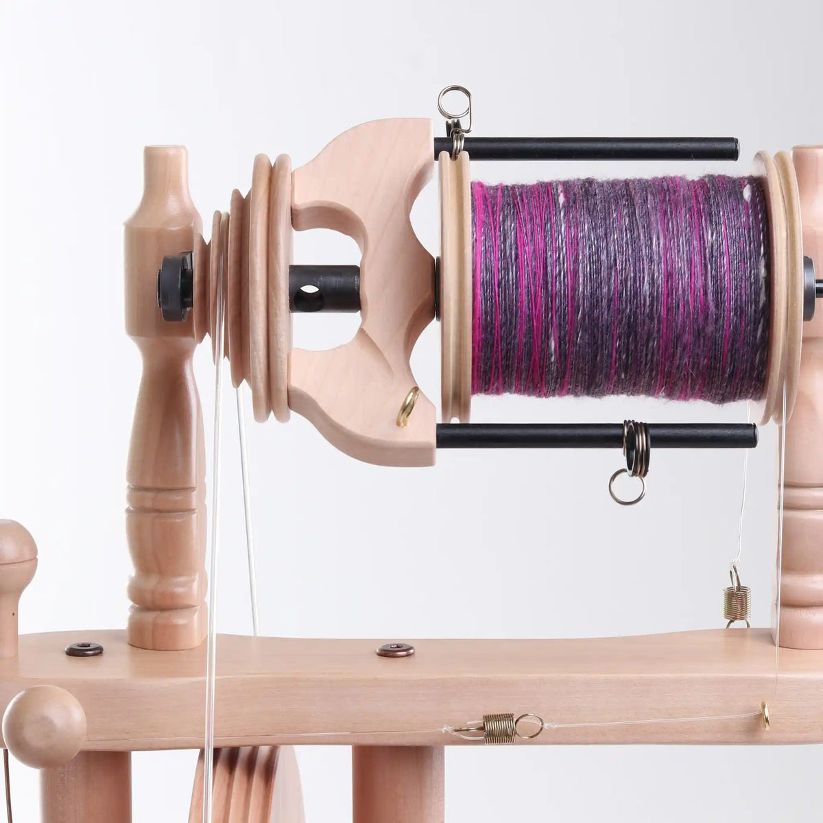 Sliding hook flyer on an Ashford Traveller 3, the yarn guides on its arms filling the bobbin evenly