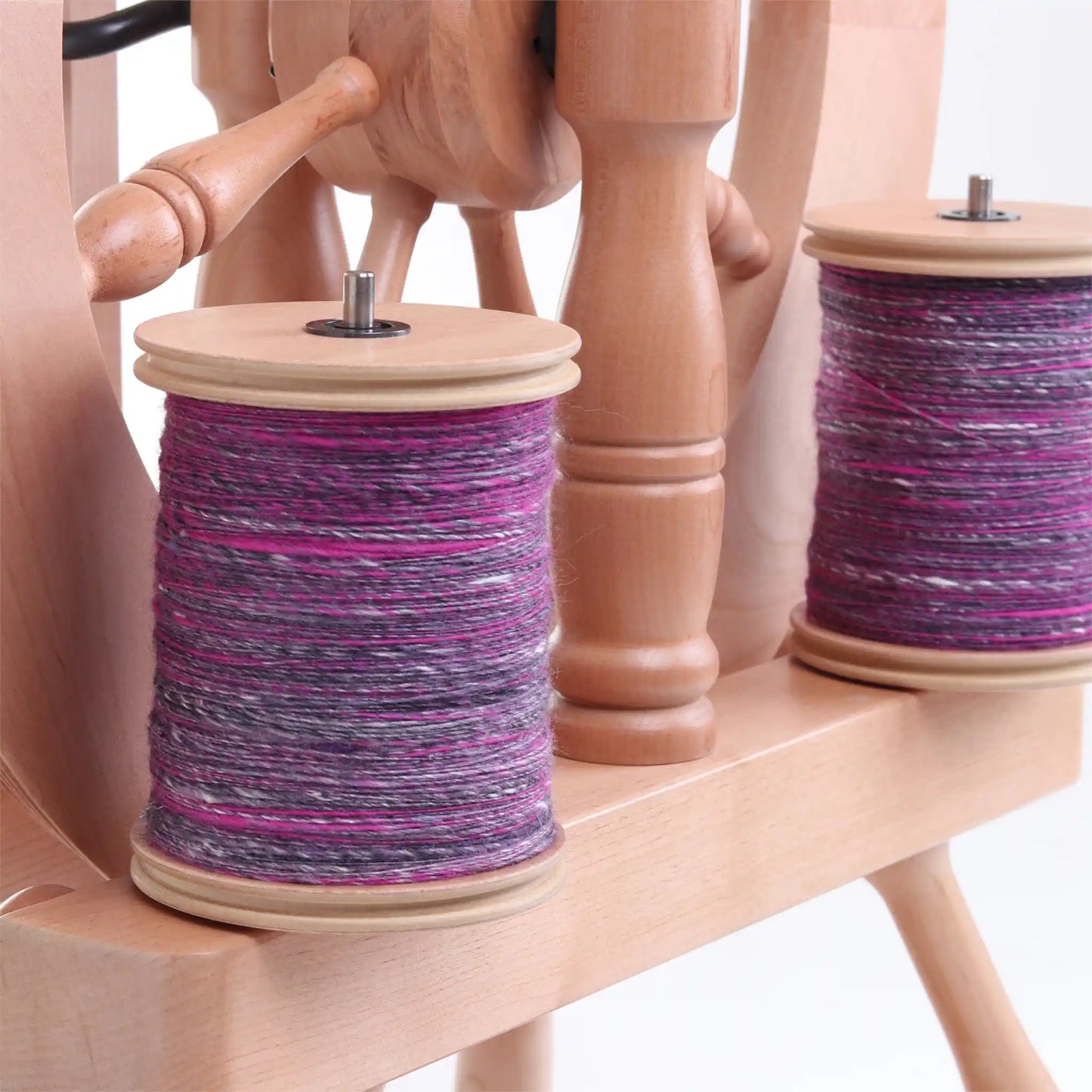 Closeup of the Ashford Traveller 3 Lazy Kate, with two bobbins full of purple yarn on the rods