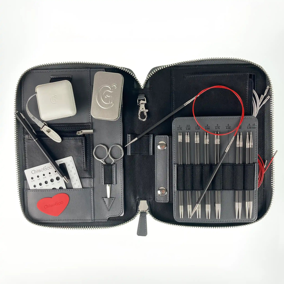 Top-down view of the open ChiaoGoo Forté 2.0 case: carbon tips, a needle on a red cable, scissors, gauge and tape measure