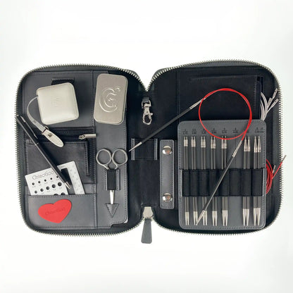 Top-down view of the open ChiaoGoo Forté 2.0 case: carbon tips, a needle on a red cable, scissors, gauge and tape measure