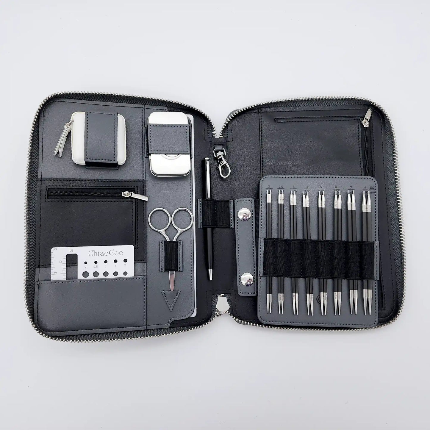 ChiaoGoo Forté 2.0 case open flat with carbon-fiber tips on the needle board, scissors, pen, gauge and tape measure