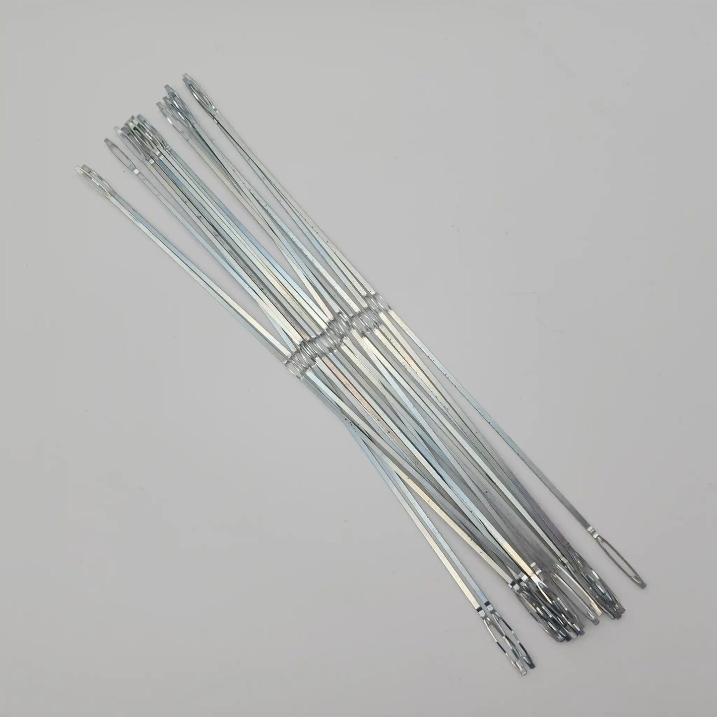 Flat steel weaving heddles fanned out to show the full length and end loops