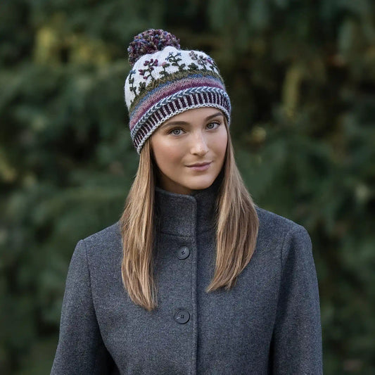 Woman wearing a colorful knitted hat adora flora hat against a blurred green background