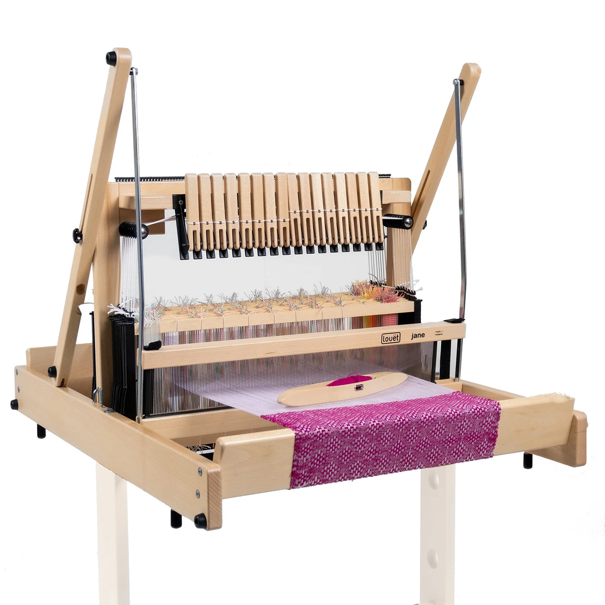 Louet Jane 16 shaft table loom with pink woven cloth on the beam and a boat shuttle in the shed