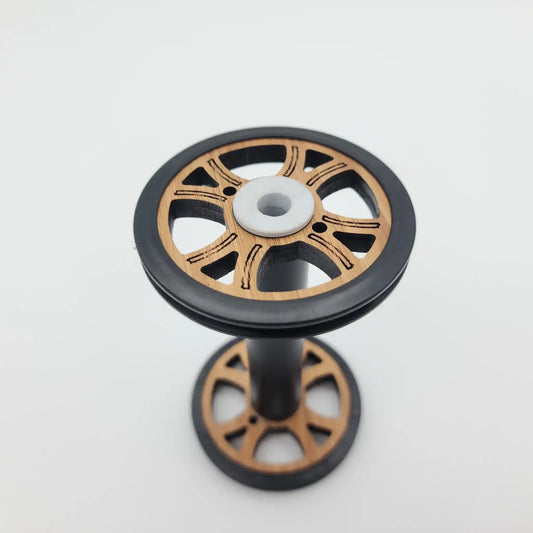 Majacraft Baby wood bobbin standing upright, showing the flange face and the tension groove in the black rim