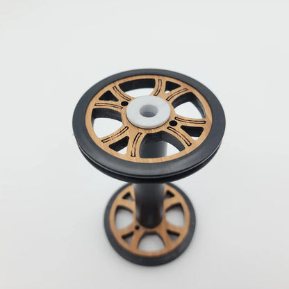 Majacraft Baby wood bobbin standing upright, showing the flange face and the tension groove in the black rim