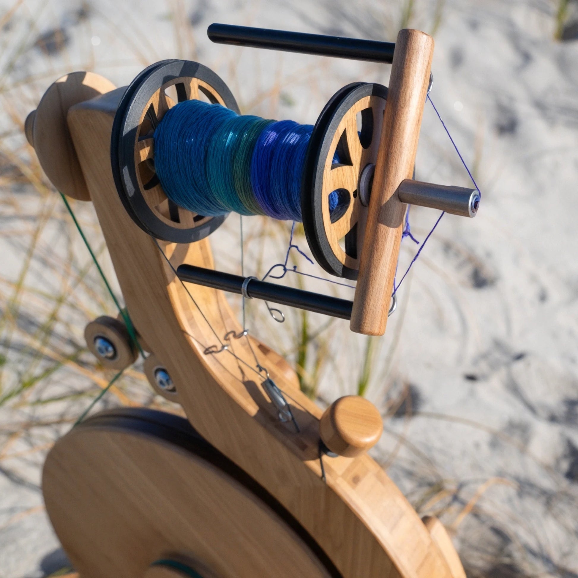 Closeup lifestyle shot of the Majacraft Luna with a bobbin full of yarn on a beach