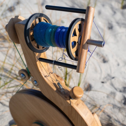 Closeup lifestyle shot of the Majacraft Luna with a bobbin full of yarn on a beach