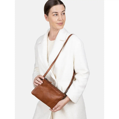 Woman in a cream coat wearing the walnut Oslo Urban crossbody on its strap