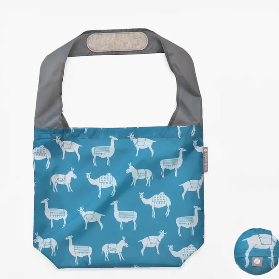 Flip & Tumble tote style bag laid flat. Bag is light blue with white pack animal printed pattern.