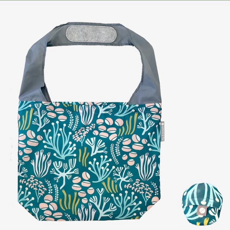 Flip & Tumble tote style bag laid flat. Bag is teal colored with a multi colored printed sea scape.