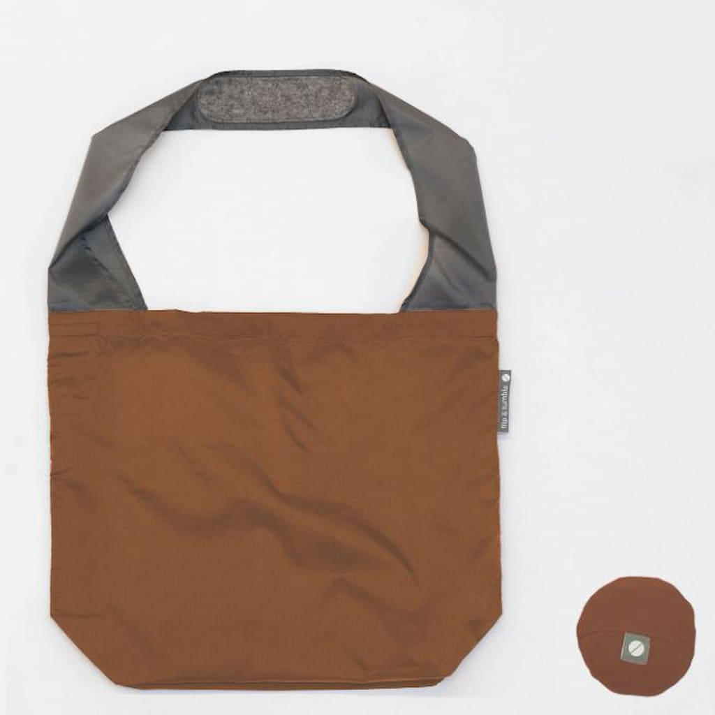 Flip & Tumble tote style bag laid flat. Bag is rust colored with grey shoulder strap.