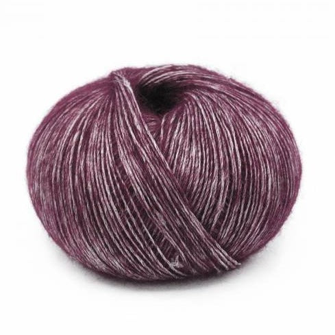 Wound ball of Mirasol Inka yarn in a slightly shiny cuprite/purple color.