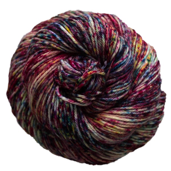 A skein of Caprino in the color Atomic 670, a speckled pink, navy, and purple colorway.
