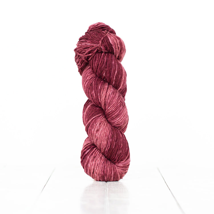 Color 6054, a variegated monochromatic skein of pinkish burgundy yarn.