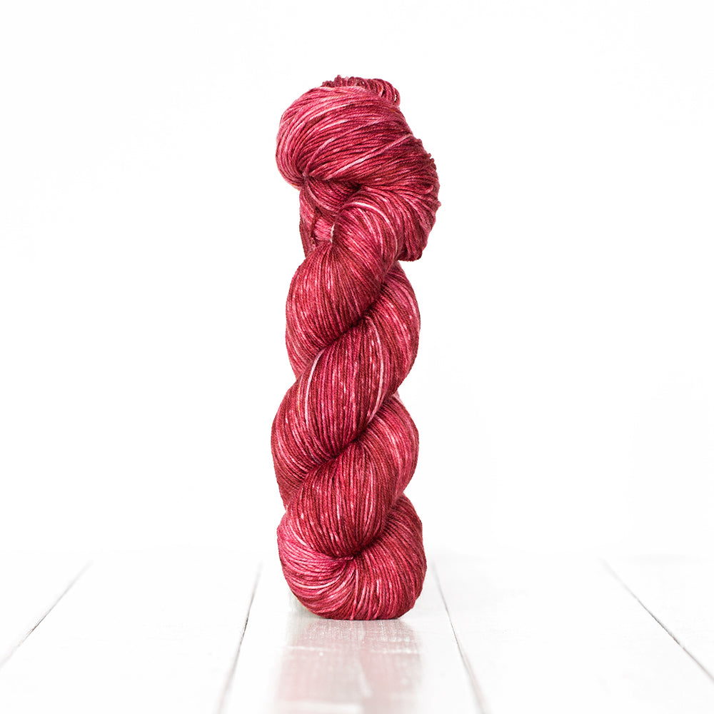 Color 3054, a variegated monochromatic skein of bright burgundy yarn.