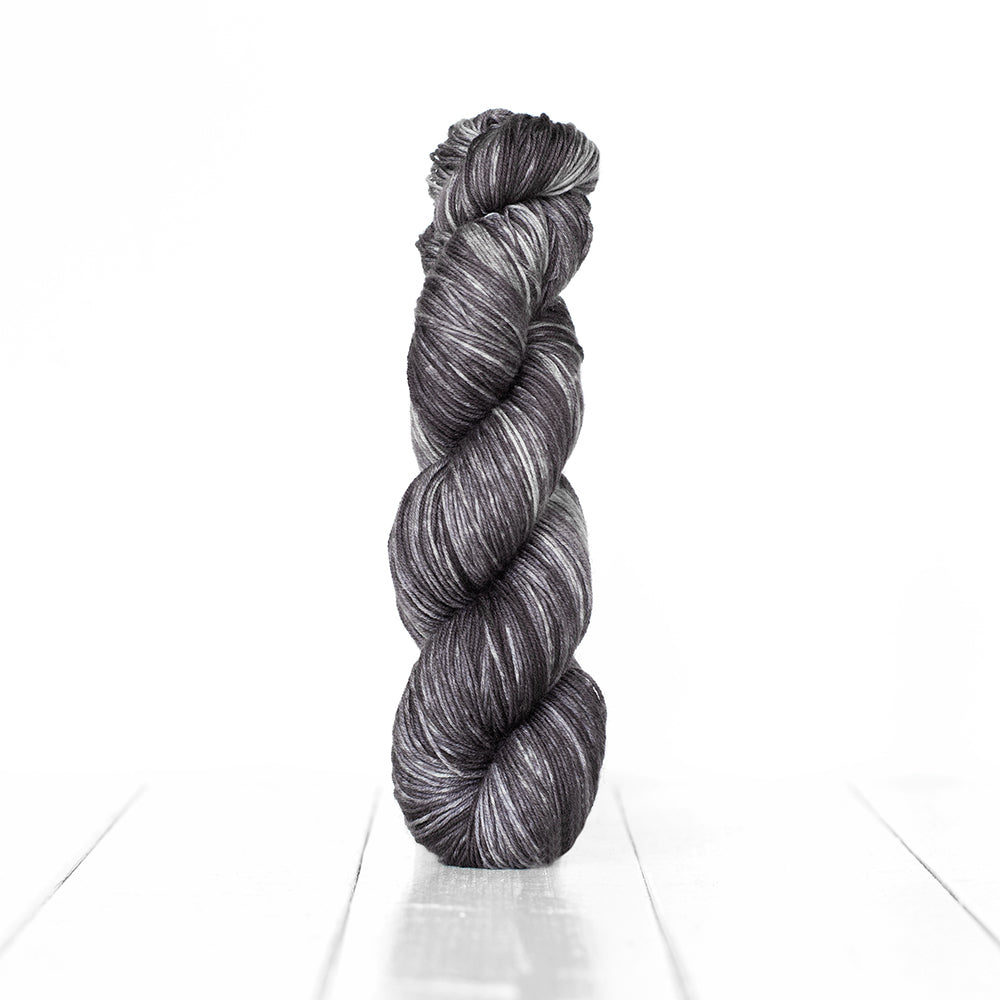 Color 3063, a variegated monochromatic skein of cool toned dark grey yarn.