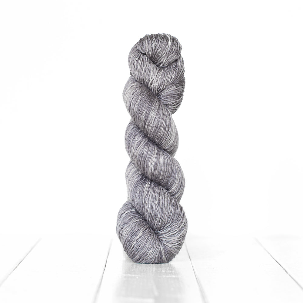 Color 3064, a variegated monochromatic skein of cool toned light grey yarn.