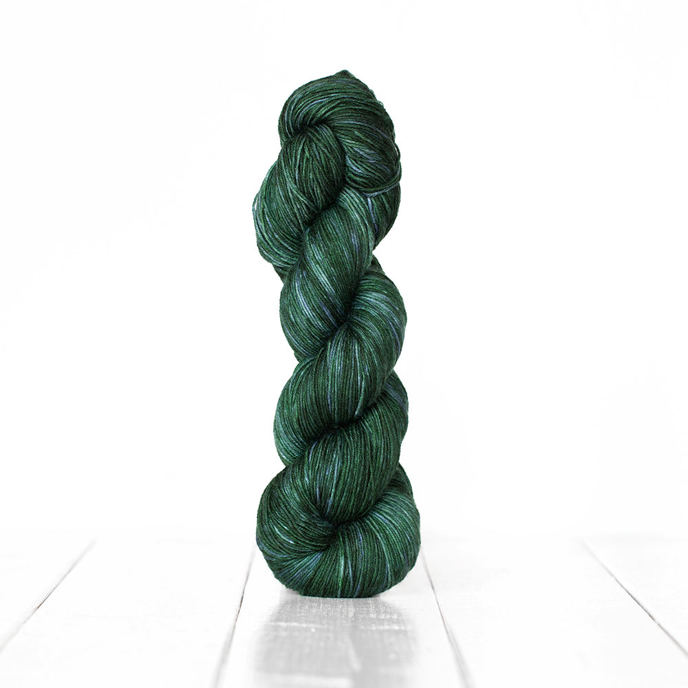 Color 3065, a variegated monochromatic skein of yarn in dark blue-green.