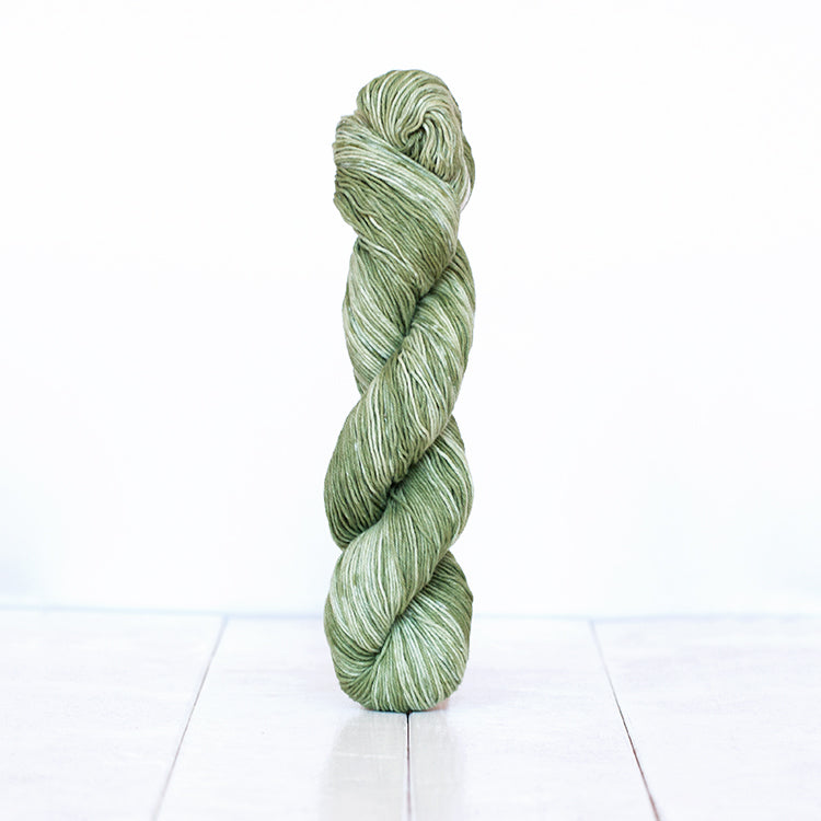 1208, a rustic olive green skein of Urth Yarn's hand-dyed Monokrom Cotton DK weight yarn.