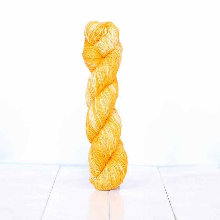 1210, a sunny yellow-orange skein of Urth Yarn's hand-dyed Monokrom Cotton DK weight yarn.