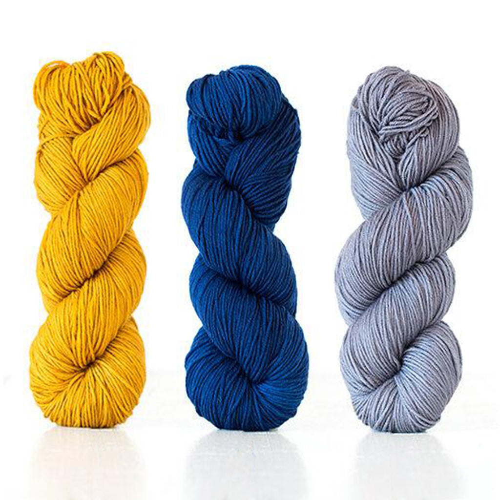Three skeins of Harvest DK in the colors Buckthorn, Indigo, and Mint.