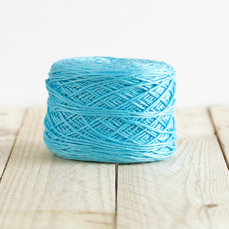 Color 5005, a bright light cyan blue cake of yarn.