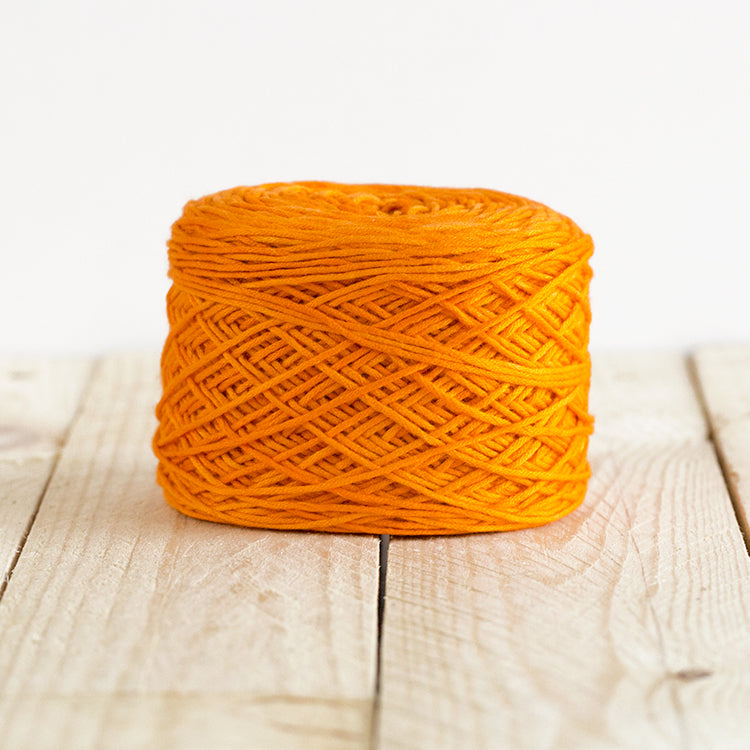 Color 5007, a bright pumpkin orange cake of yarn.