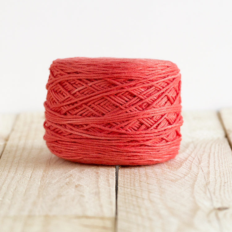 Color 5018, a bright coral red cake of yarn.