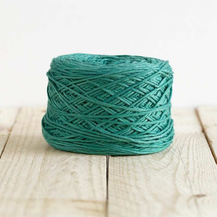 Color 5019, a dark seafoam cake of yarn.
