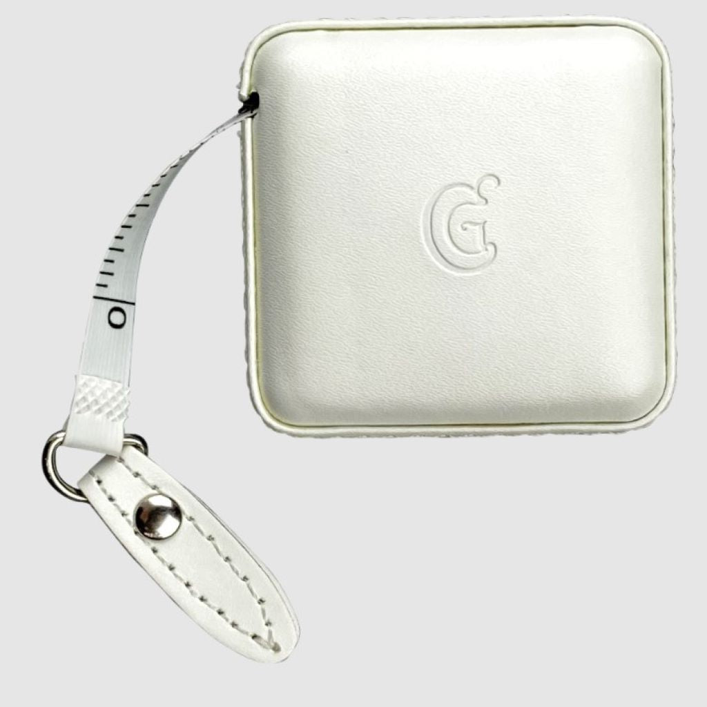 A white, square tape measure in a faux leather case